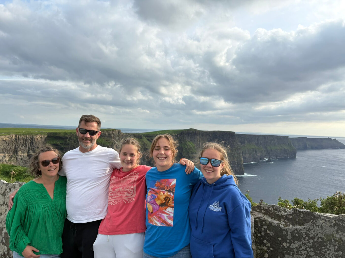 A family with arms around each other at an ocean cliff lookout